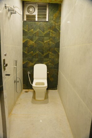 Un baño pequeño y estrecho con inodoro, ducha y ventana.