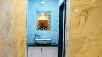Un baño con pared de mármol, un lavabo con espejo decorativo y un perchero para toallas.