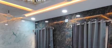 Habitación de hotel con dos camas, un ventilador de techo y suelo de mármol.