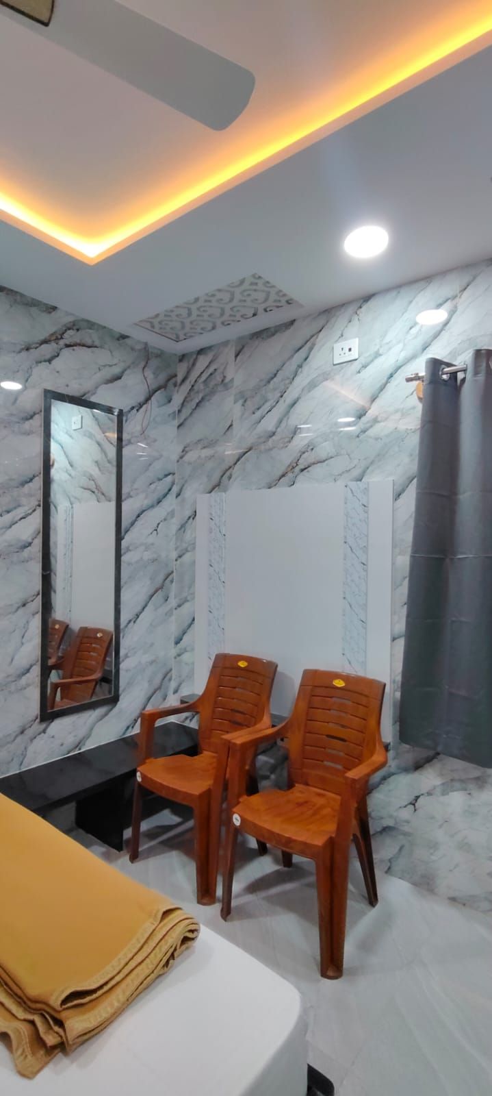 Un baño con paredes de mármol, sillas de madera, un espejo y una toalla.