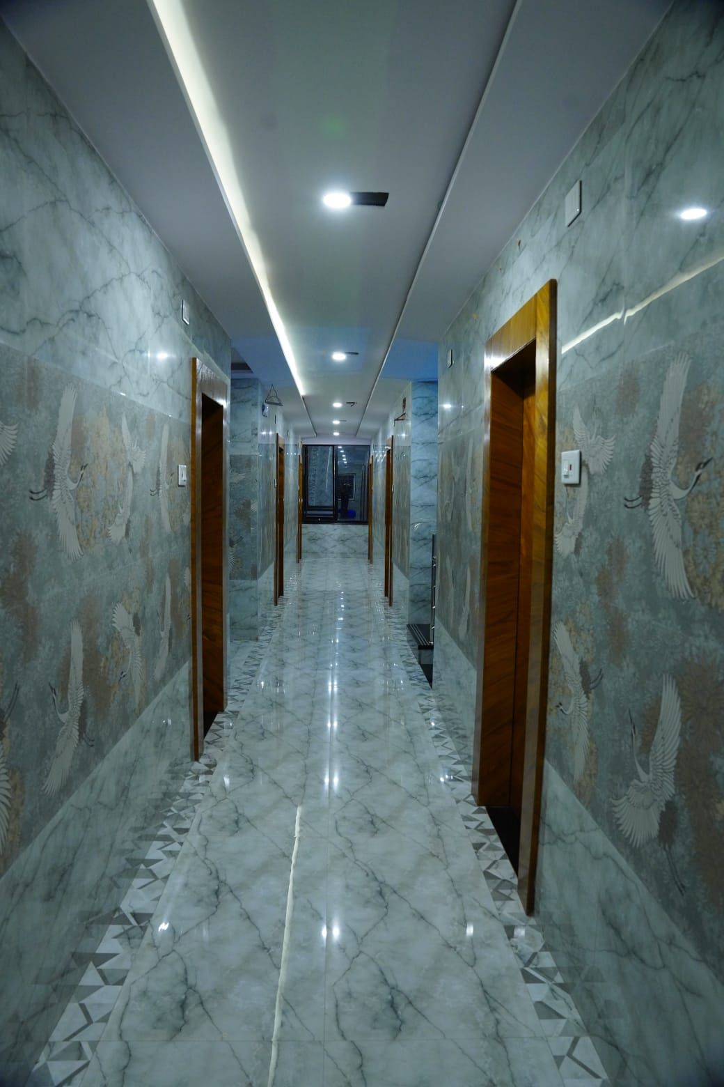 A hallway with marble floors and walls, featuring a central corridor with doors on either side.