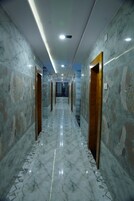 Un pasillo con suelos y paredes de mármol, que presenta un corredor central con puertas a ambos lados.