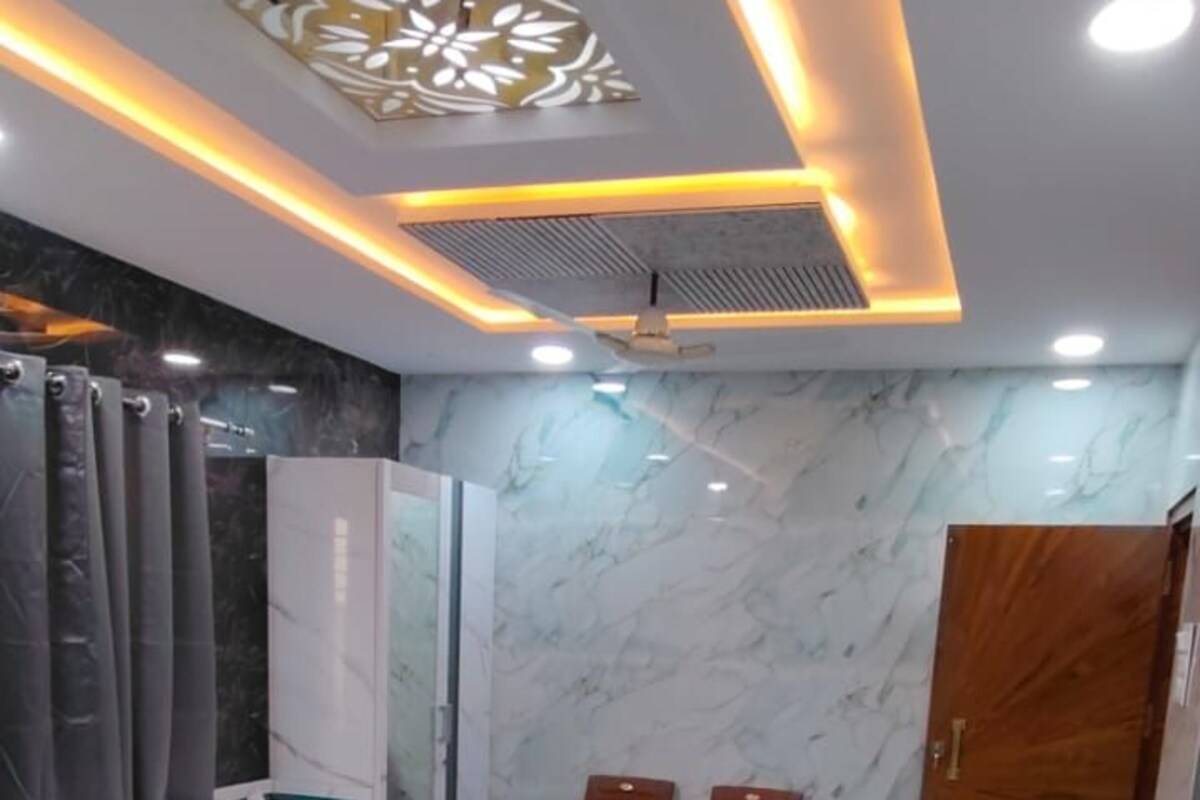 A hotel room with two beds, marble flooring, a wooden door, and a ceiling with recessed lighting.