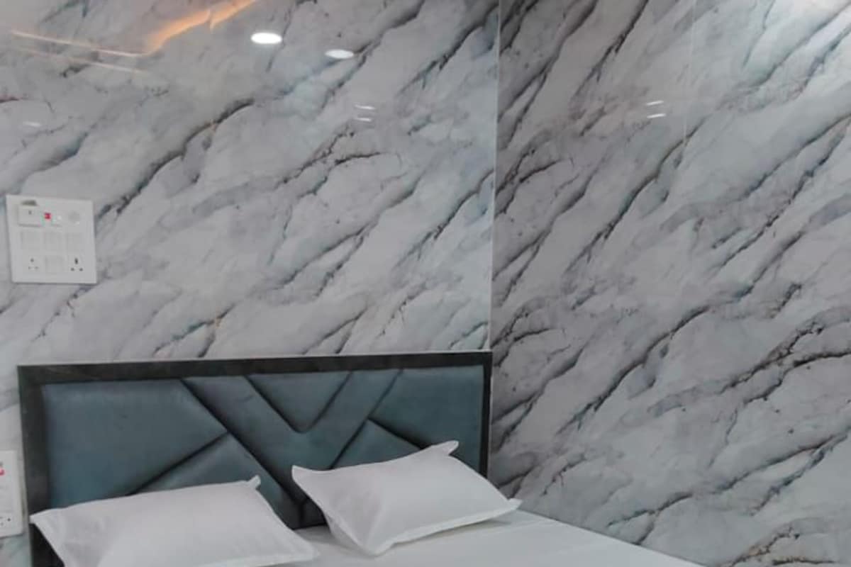 A hotel room with a bed, marble-patterned walls, a ceiling fan, and recessed lighting.