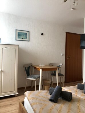 Una habitación de hotel con una cama, dos sillas, una mesita, un armario y un televisor.
