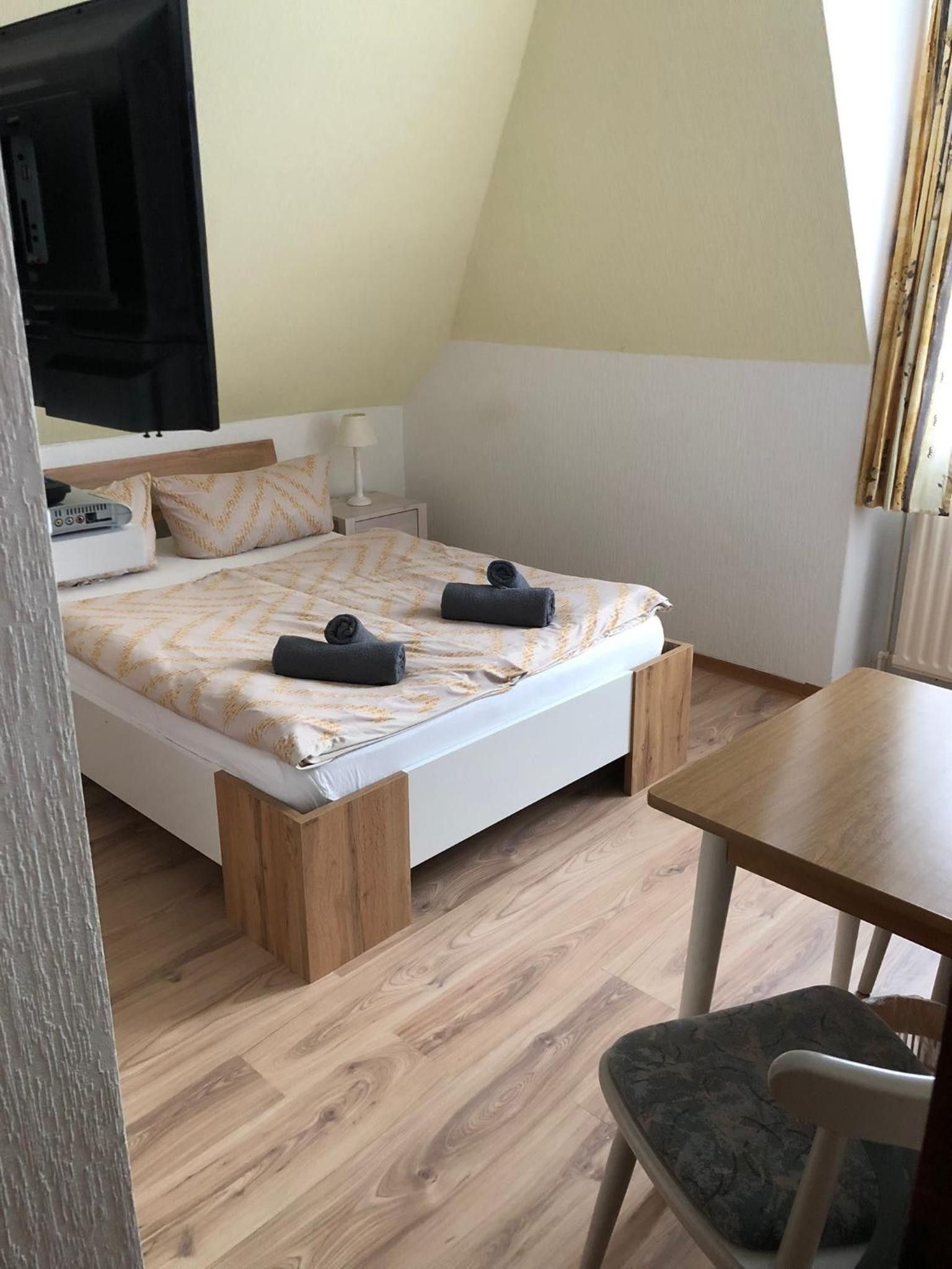 Un dormitorio con cama, mesita de noche, silla y un radiador.