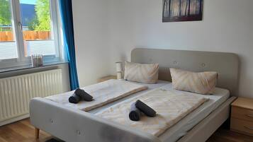 Quarto moderno com uma cama grande, janela com cortinas, radiador e um quadro na parede.