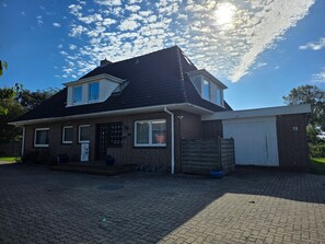 Une maison à deux étages avec un garage, une façade en briques et une allée pavée.