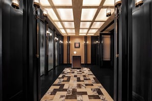 A hallway with a checkered marble floor, dark walls, and wall-mounted lighting fixtures. - Blossom Manoir Jiefangbei Chongqing (Chongqing)