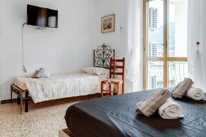 A room with a bed, a chair, a television mounted on the wall, and a window with a view of buildings. - GuestHost - Vacation Home 1 - Bright Apartment x8 (La Spezia)