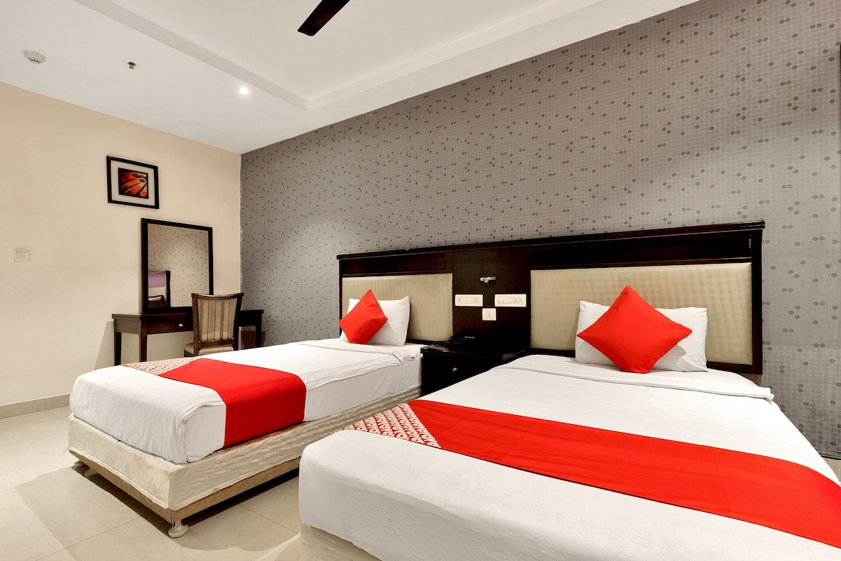 A hotel room with two beds, each with a red and white bedspread, a wooden headboard, and a nightstand with a lamp.