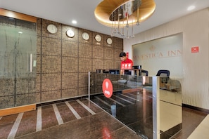 Un espace d’accueil au design moderne, comprenant une cloison en verre, une horloge et une enseigne indiquant le nom de l’hôtel : « MAJESTICA INN & BANQUETS ».
