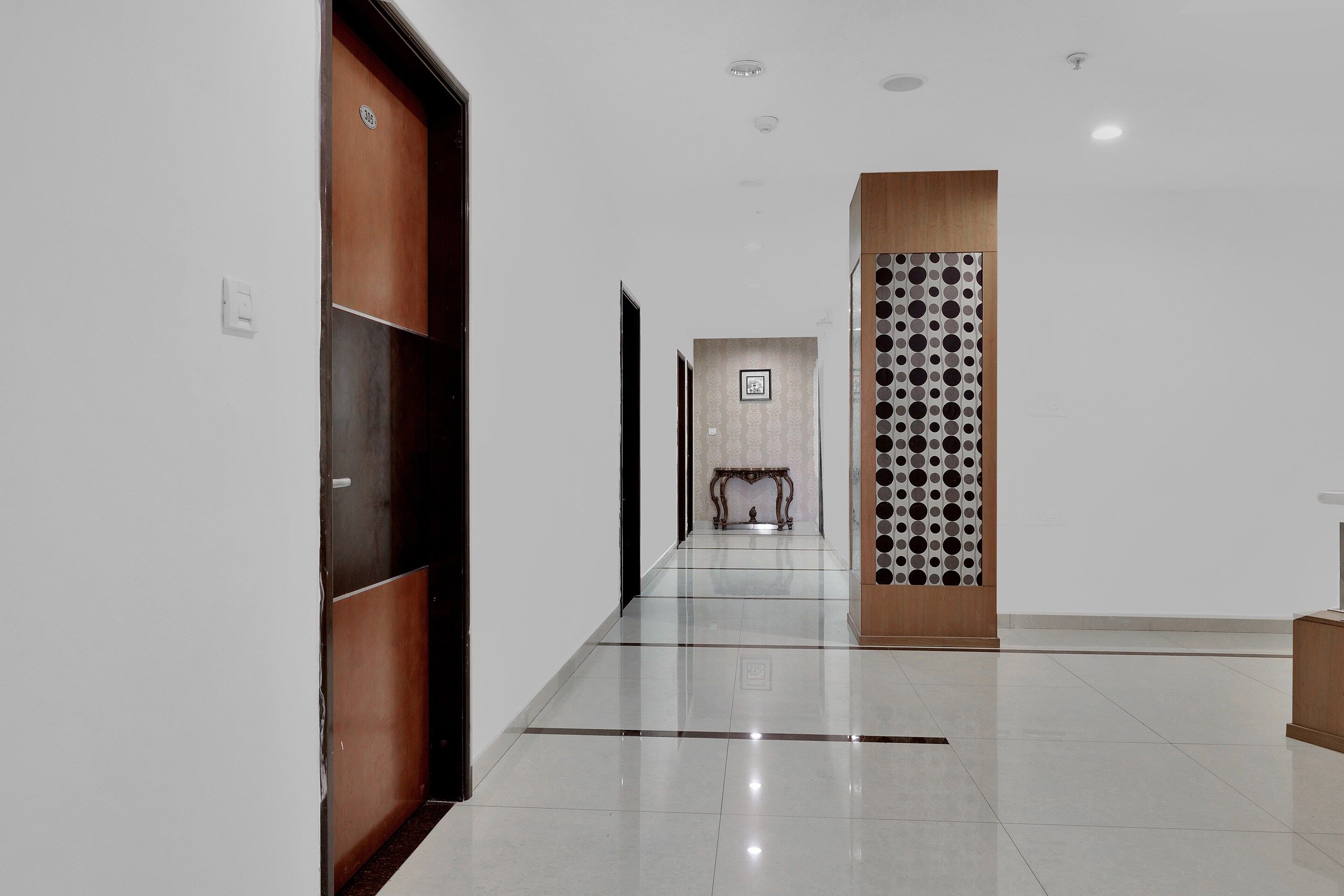 Um corredor com porta de madeira, parede estampada e chão de azulejos.