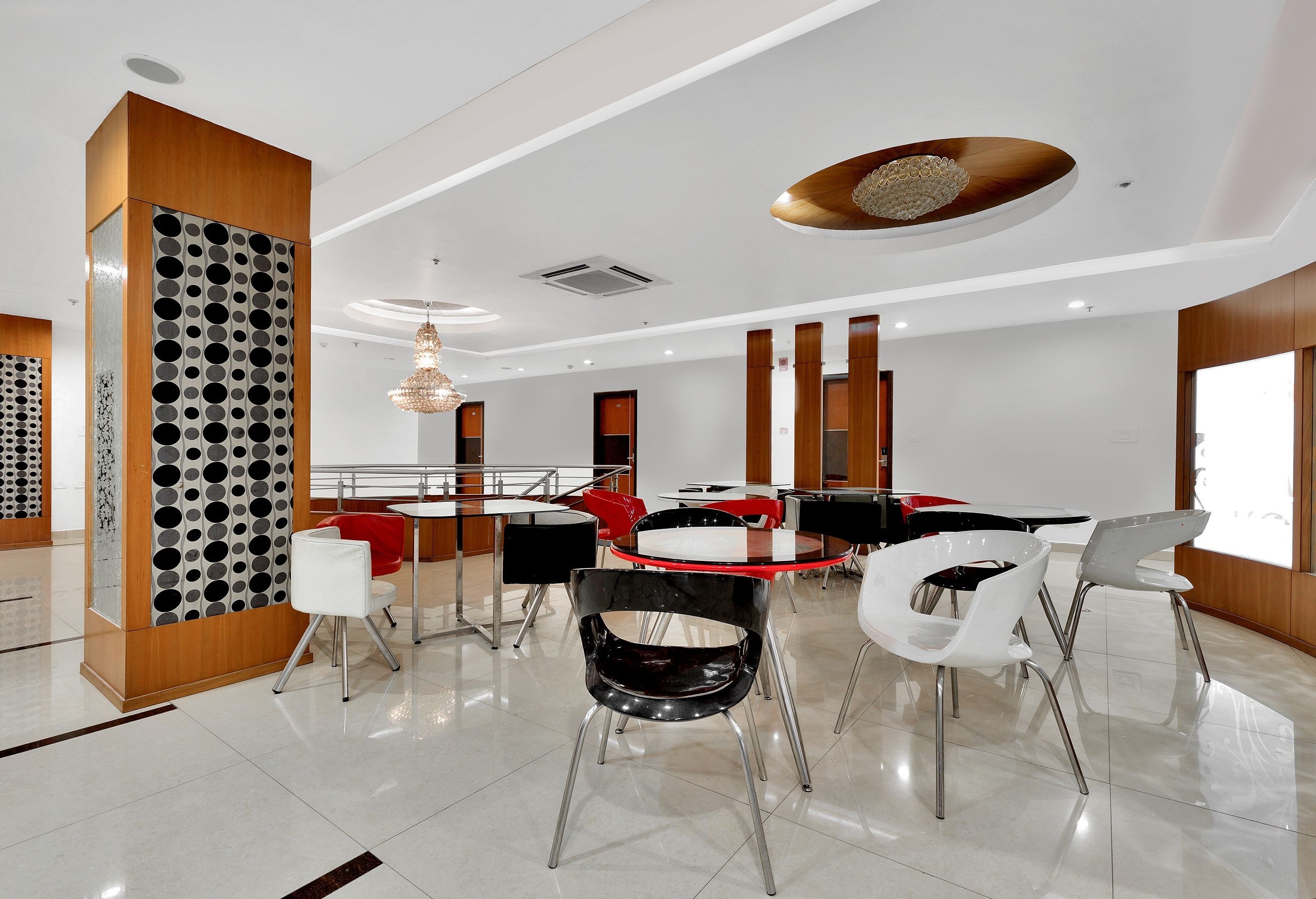 Uma área de jantar moderna com uma mesa redonda central, rodeada por cadeiras de pernas metálicas e um detalhe decorativo no teto.