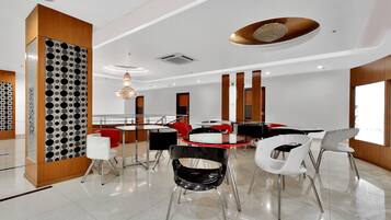 Uma área de jantar moderna com uma mesa redonda central, rodeada por cadeiras de pernas metálicas e um detalhe decorativo no teto.