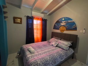 Quarto com cama, um quadro e um ventilador de teto.