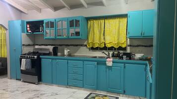 Una cucina con pensili color acquamarina, un fornello a gas e una tenda alla finestra color giallo.