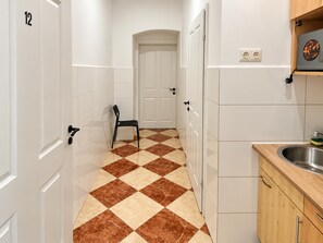 A hallway with a checkered floor, a door at the end, and a kitchen area with a sink and cabinets. - Unpack and Stay Vienna 1BR Westbahnhof (Vienna)