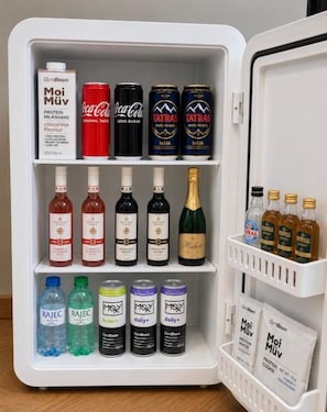 A refrigerator stocked with various beverages including protein shakes, Coca-Cola, and Tatra beer.