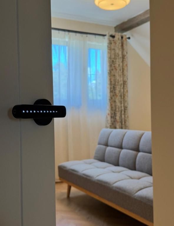 A room with a sofa, a door with a lock, and a window with curtains.