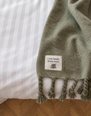 Manta de lã verde com etiqueta sobre a cama.