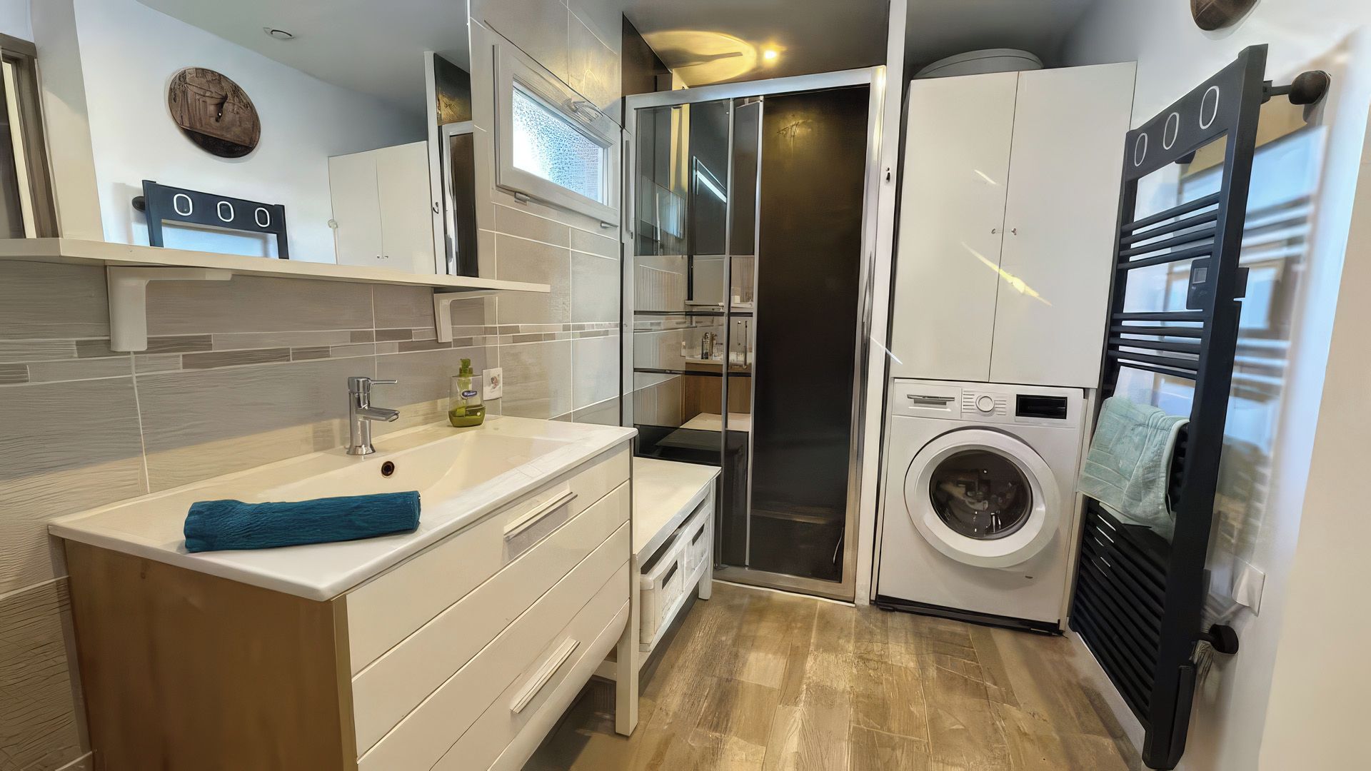 Une petite salle de bain comprenant un lavabo, un miroir et un lave-linge encastré.