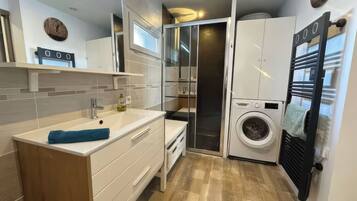 Une petite salle de bain comprenant un lavabo, un miroir et un lave-linge encastré.