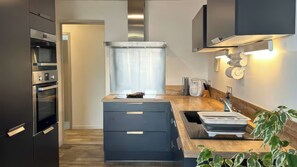 Una cocina moderna con electrodomésticos integrados, una isla central y vistas al salón contiguo.