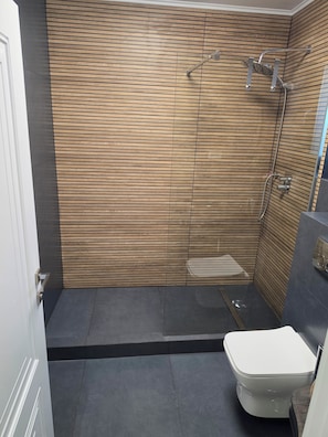 Een badkamer met een wand van houten latten, een douche en een toilet.