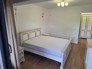 Een slaapkamer met een bed, nachtkastjes, een kledingkast en een plafondlamp.