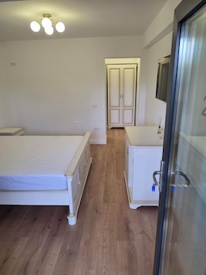 Een slaapkamer met een bed, een dressoir en een kledingkast.