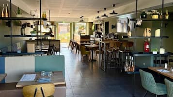 A modern restaurant with high tables and booths, a bar area, and shelves with bottles.