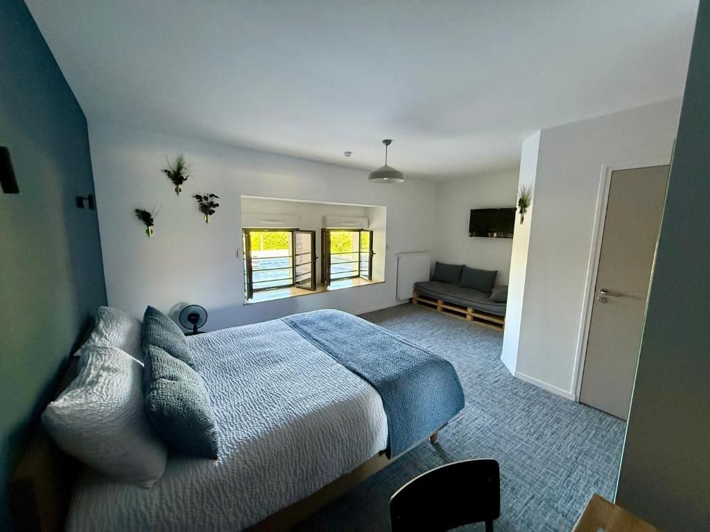 Un dormitorio moderno con una cama, una silla, un sofá, una ventana y una puerta.