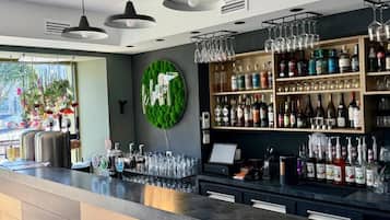Een bar met een aanrecht, drankflessen op de planken en hangende glazen.