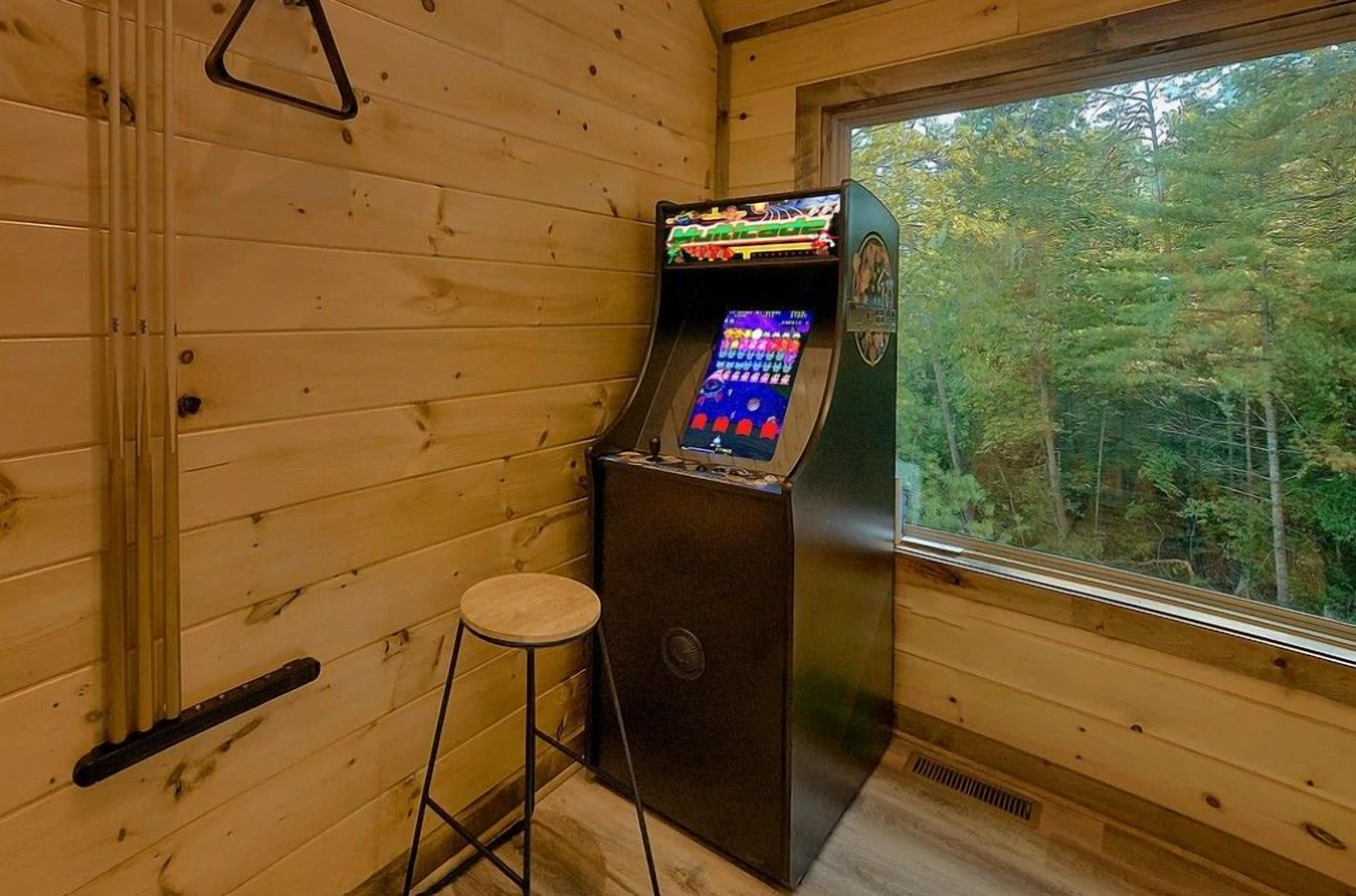 A wooden cabin interior with a slot machine, a stool, and a window overlooking a forest.