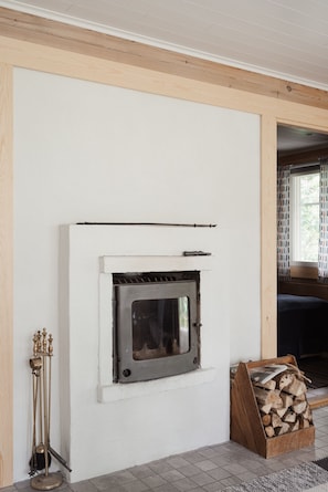 A fireplace with a metal grate, a log storage box, and a chimney.