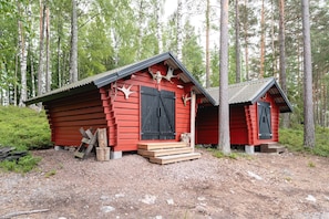 Two red wooden cabins with black shutters, set in a forest with tall trees. - Villa Casanova - Private Seaside Cabin (Porvoo)