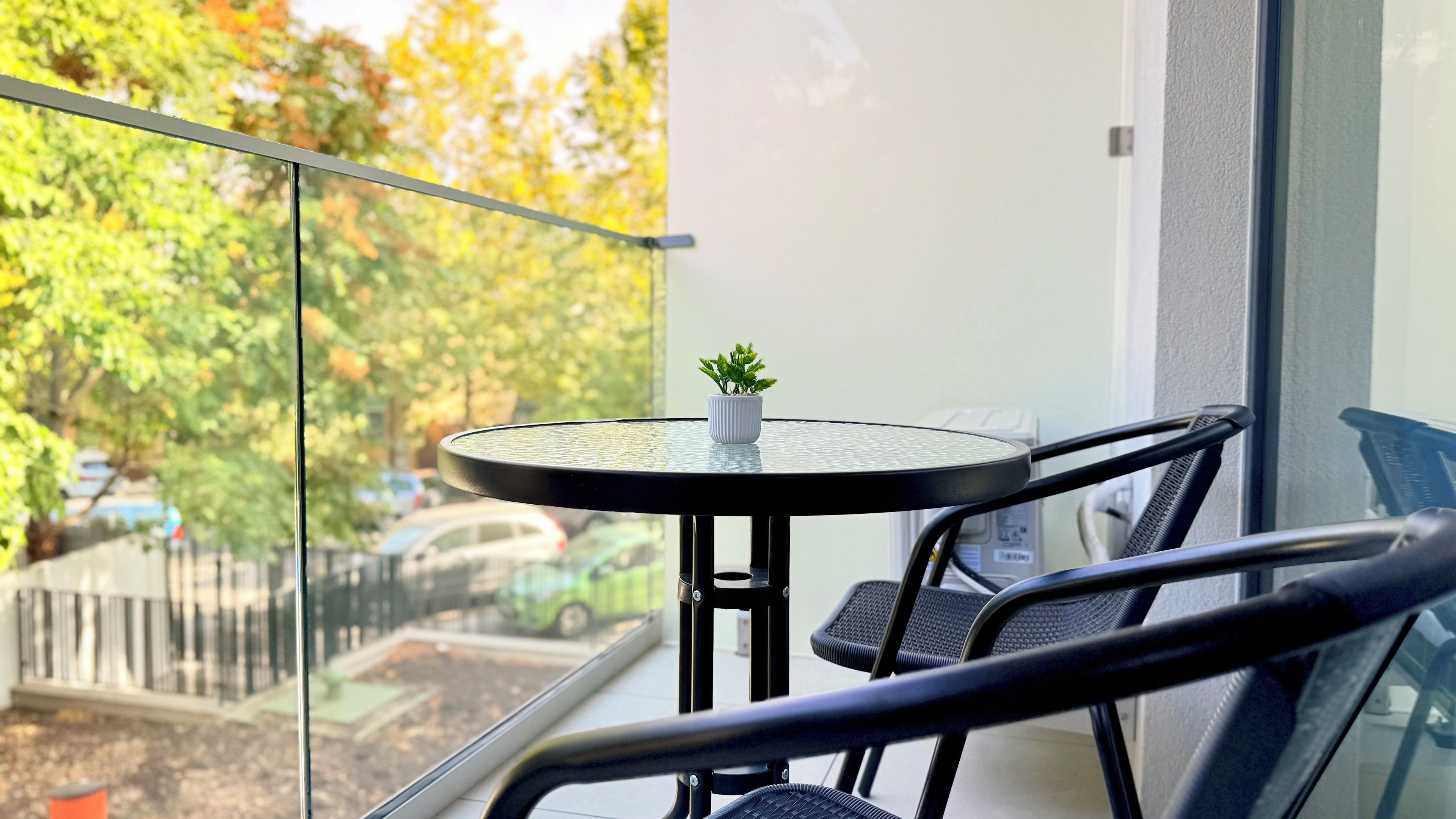 A balcony with a round table, a potted plant, and a chair.
