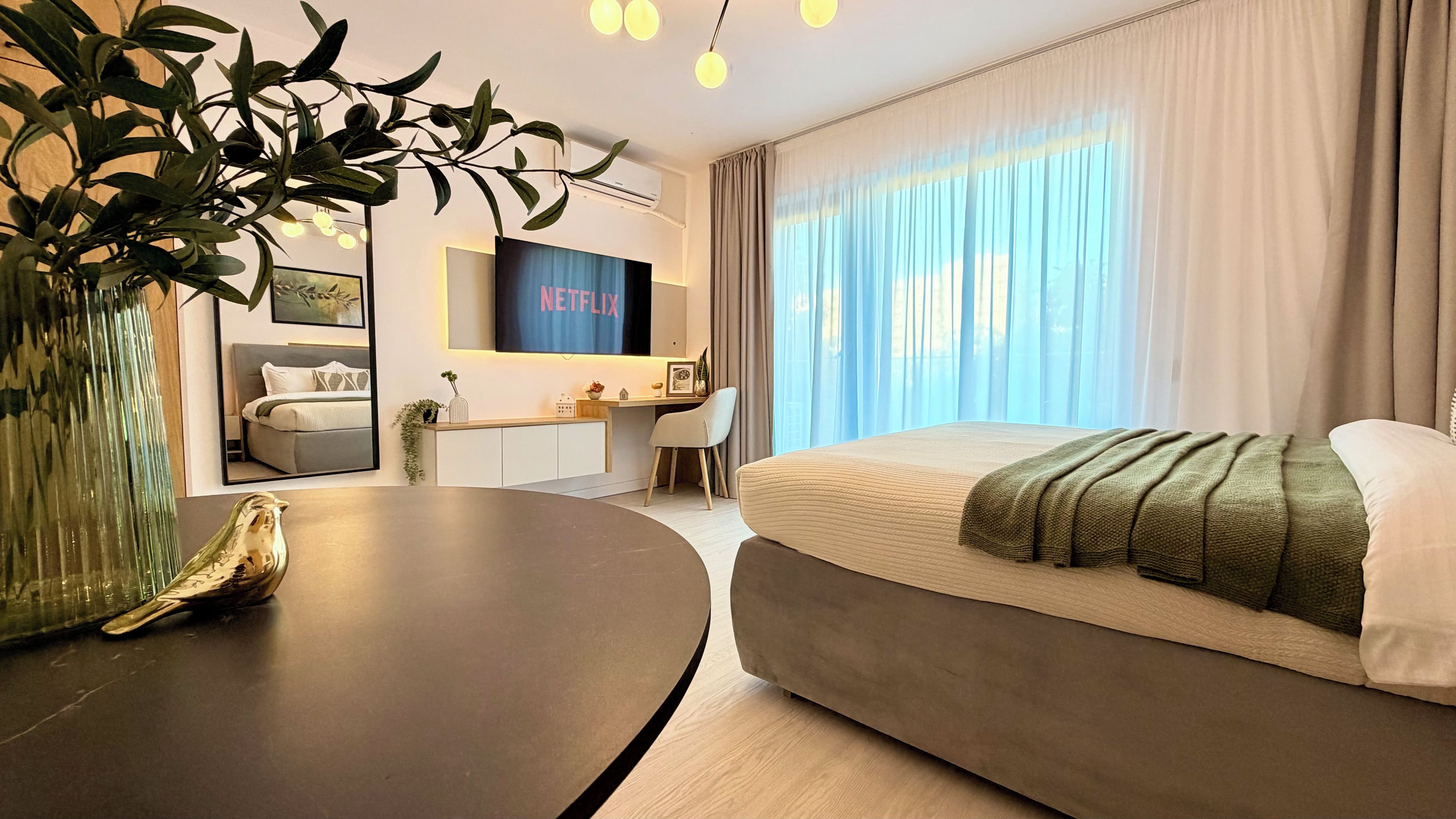 Una habitación de hotel moderna con cama, escritorio, televisión y zona de comedor.