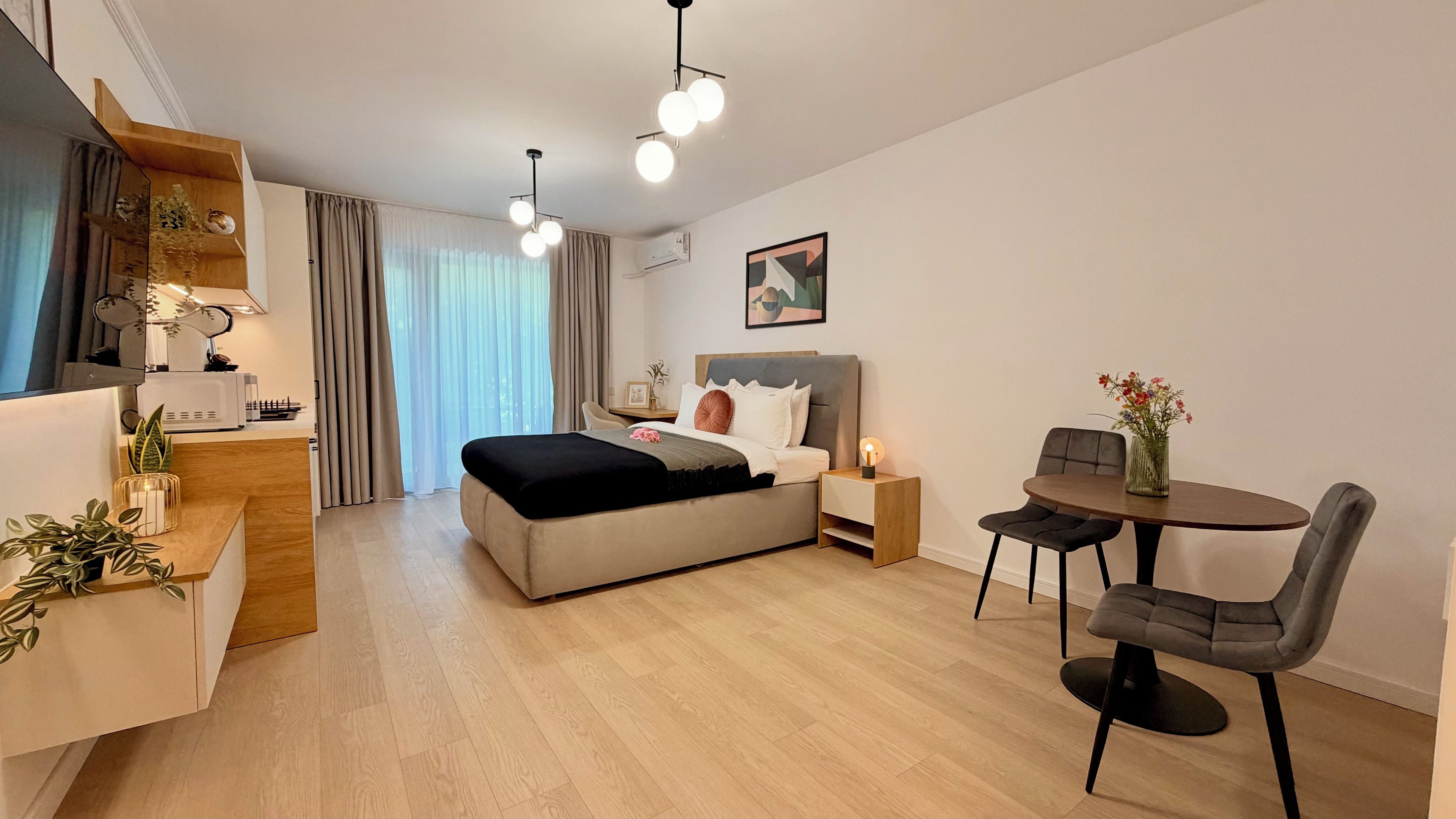 A modern bedroom with a bed, bedside table, and a dining area with chairs and a table.