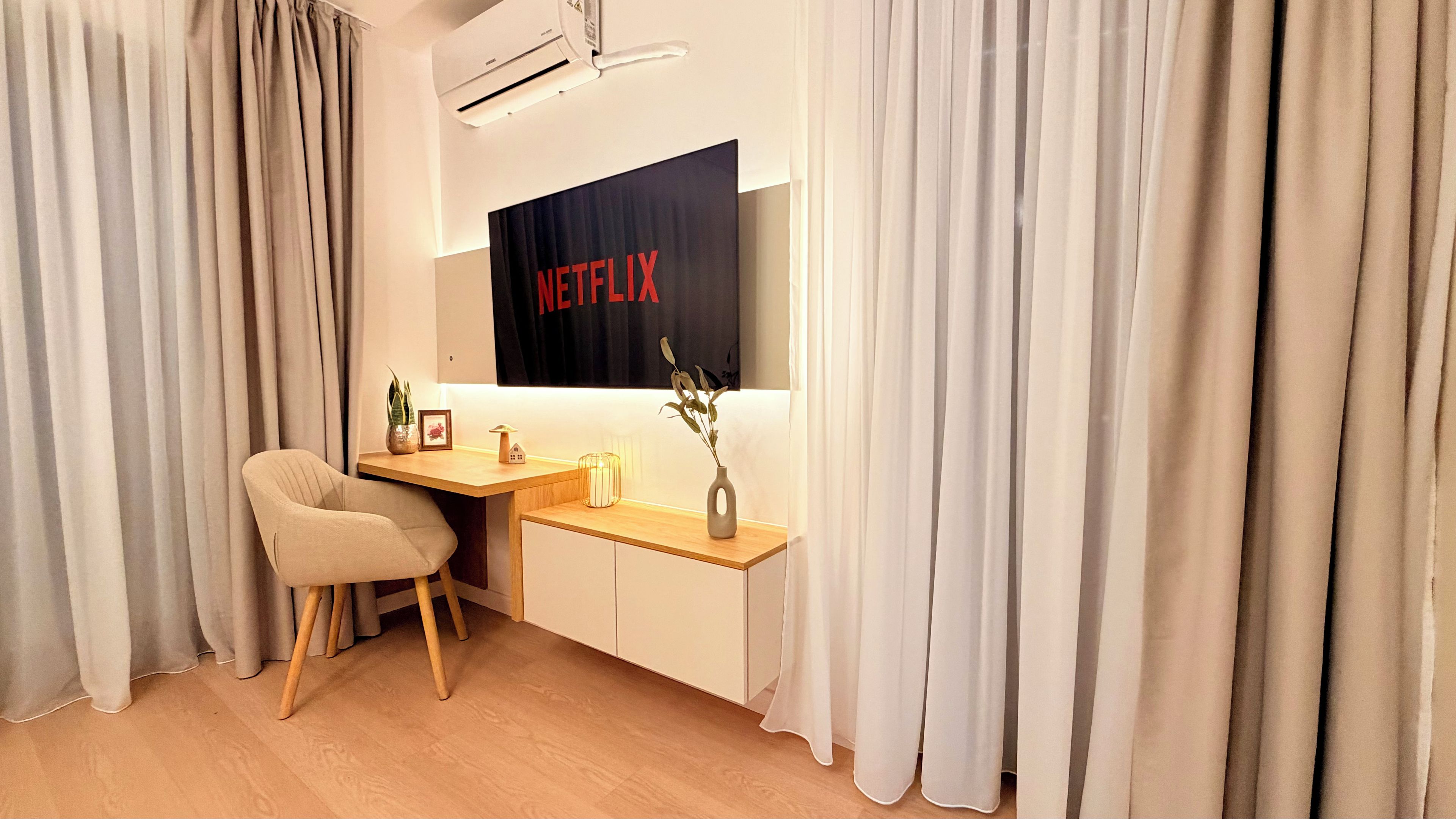 A modern room with a desk, chair, and a wall-mounted air conditioner.