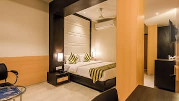 Una habitación de hotel con cama, mesita de noche, silla y escritorio con computadora.