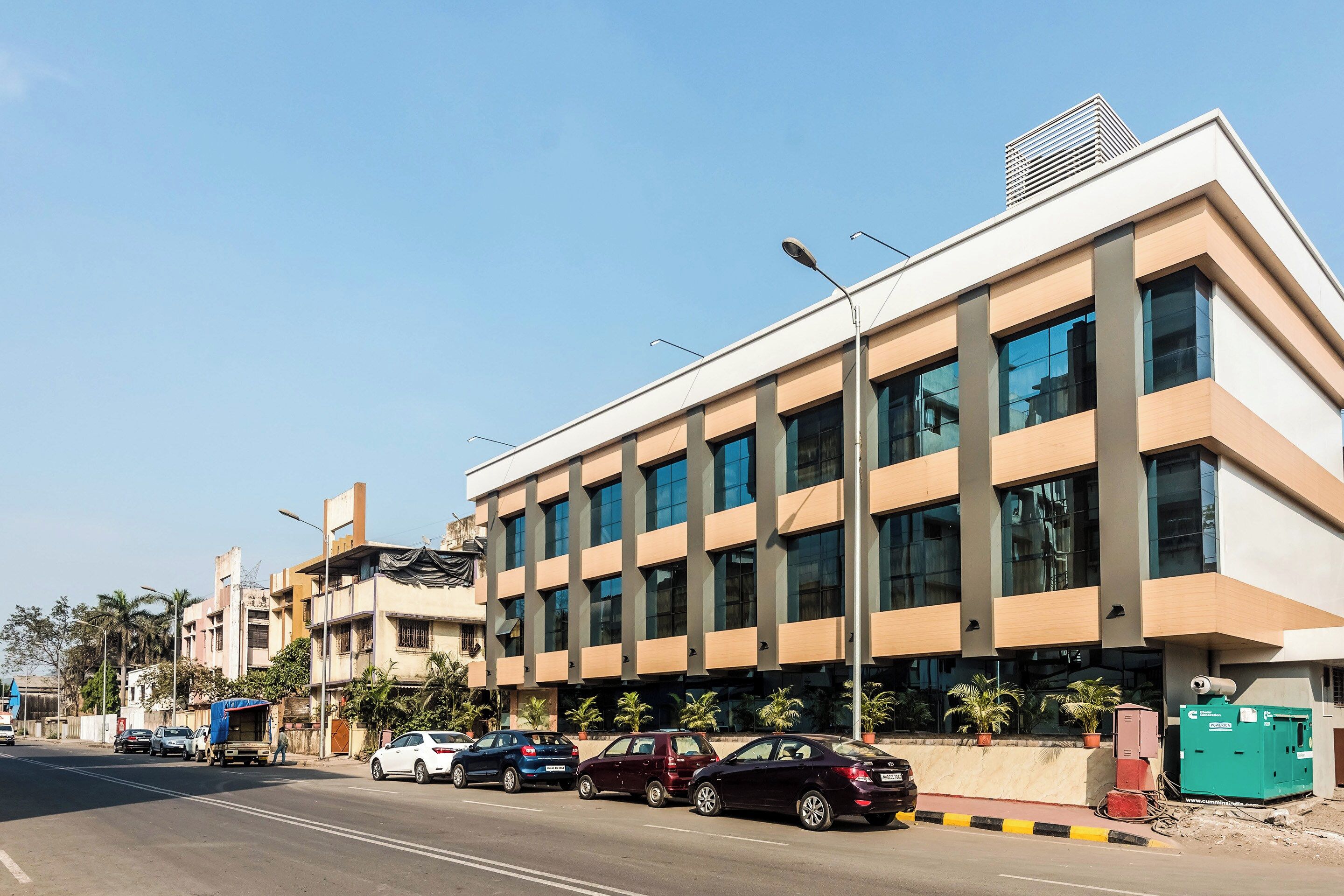 A modern building with a flat roof, large windows, and a street in front.