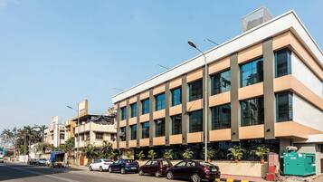 A modern building with a flat roof, large windows, and a street in front.