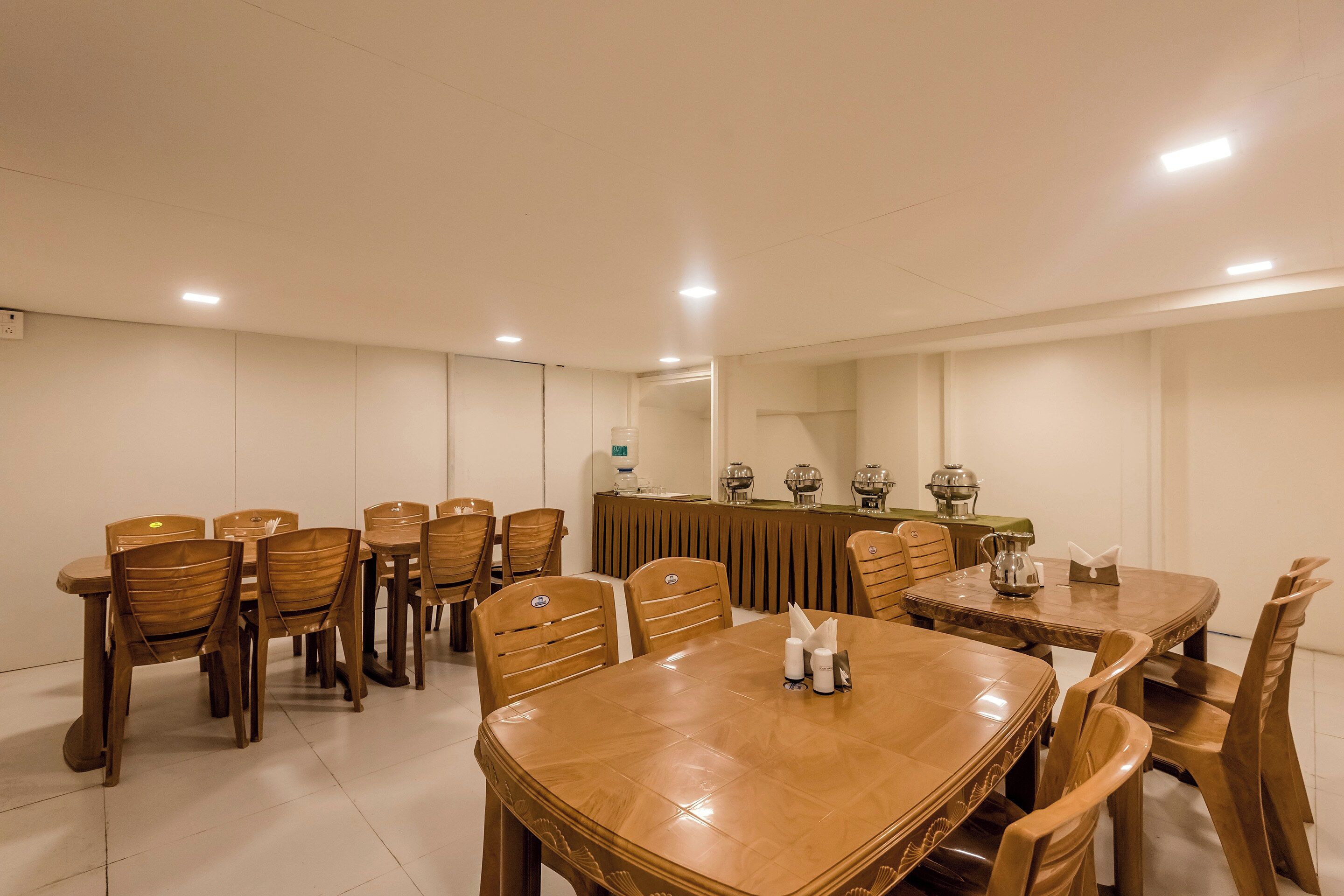 A conference room with a long table, multiple chairs, and a buffet setup with food warming equipment.