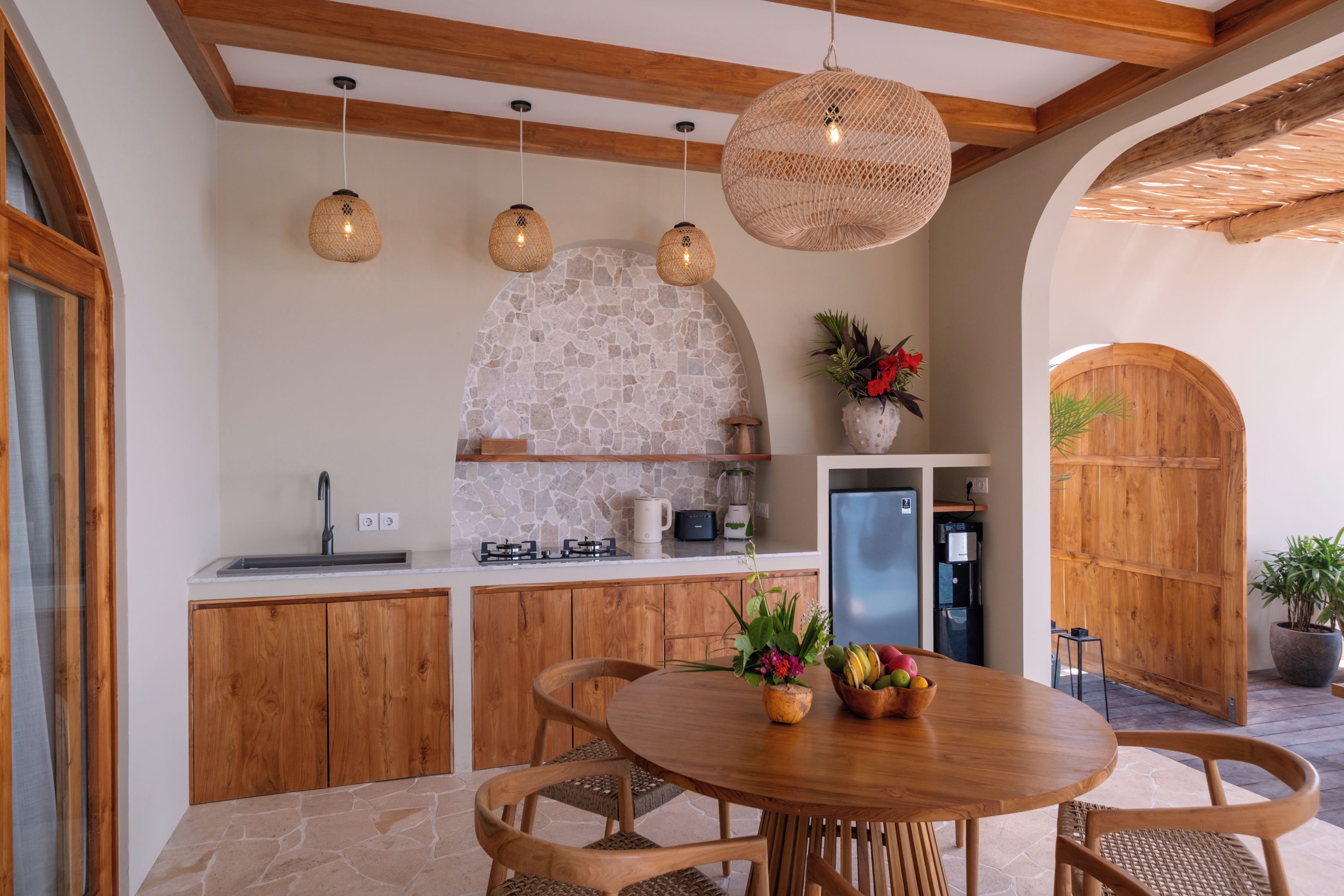 A kitchen with wooden cabinets, a stone backsplash, and hanging pendant lights.