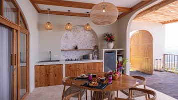 A modern kitchen with wooden cabinets, a stone backsplash, and a dining area with a round table and chairs.