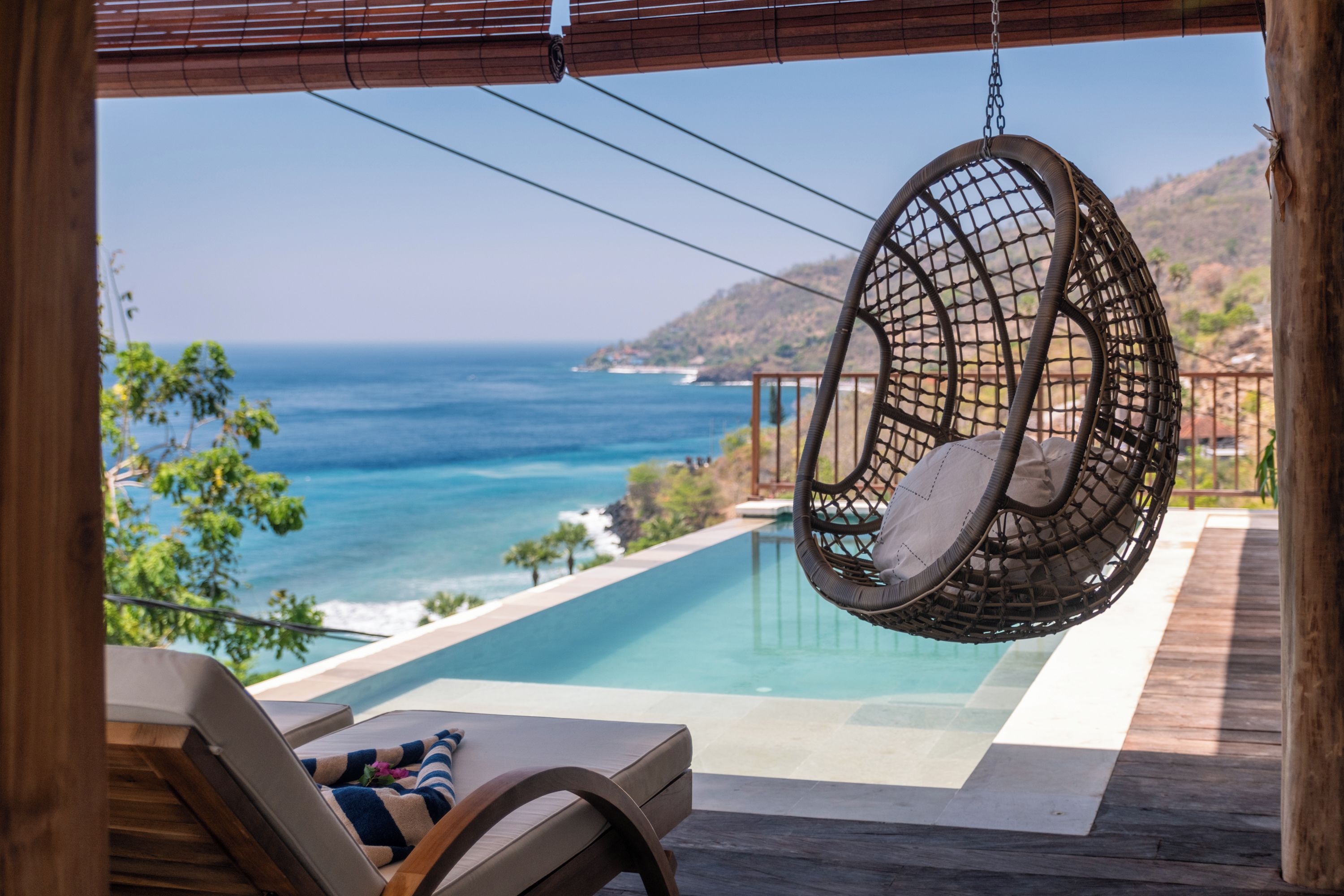 Una silla colgante con vistas a una piscina y al océano.