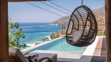 Una silla colgante con vistas a una piscina y al océano.