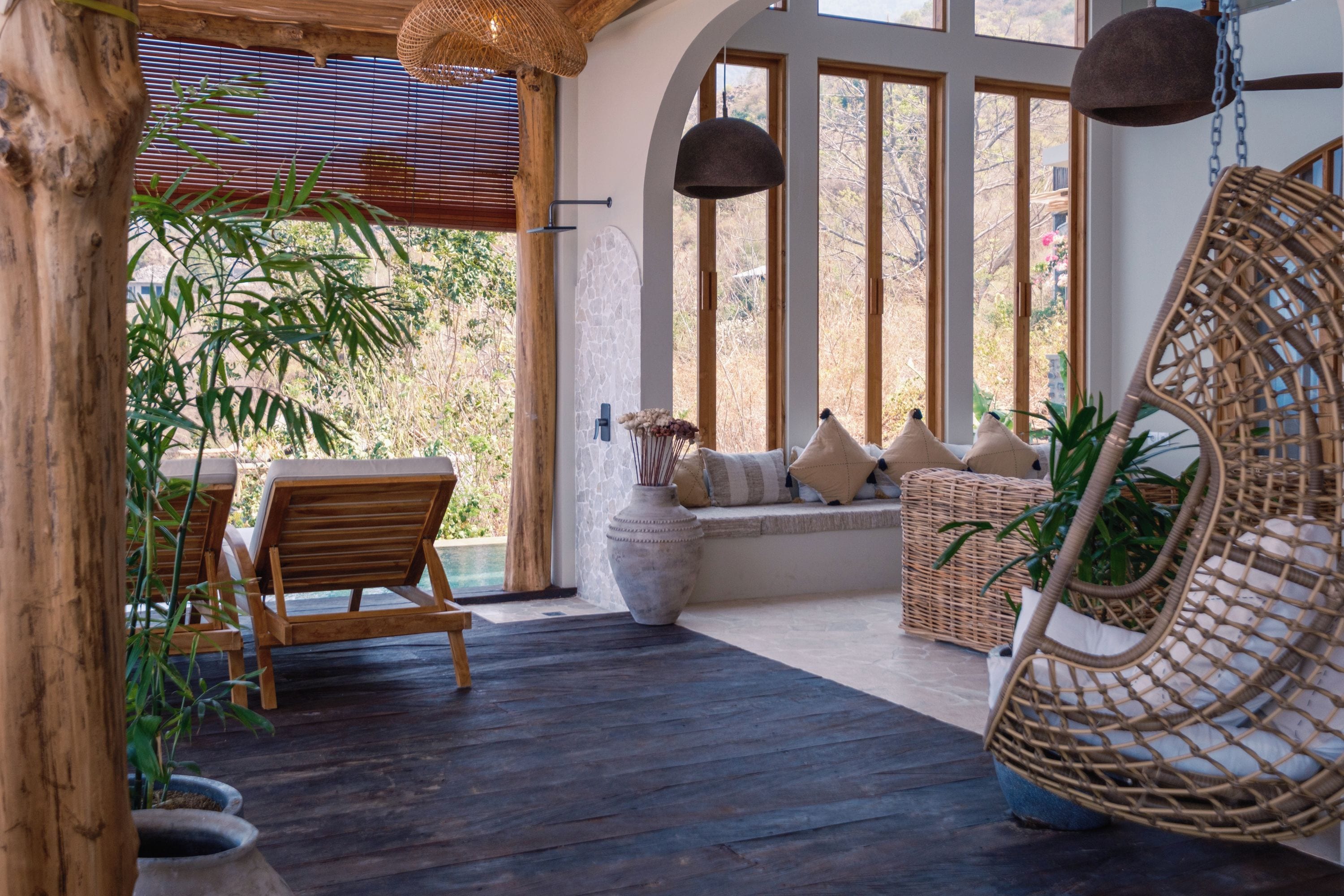 Une terrasse en bois avec une chaise en osier et un coin salon confortable agrémenté de coussins.